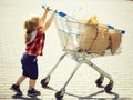 Cute boy pushing shopping trolley