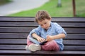 Cute boy, read a book in the park, sitting on bench, summertime Royalty Free Stock Photo