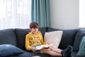 A boy reading the book on the couch in free time