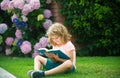 Cute boy reading book on green grass. Royalty Free Stock Photo