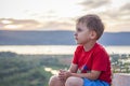 Cute Boy in a red T-shirt on the background of a stunning sunset. Journey. The face expresses natural joyful emotions. Not staged Royalty Free Stock Photo