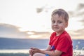 Cute Boy in a red T-shirt on the background of a stunning sunset. Journey. The face expresses natural joyful emotions. Not staged Royalty Free Stock Photo