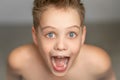 A cute boy screams with joy. A freestanding young man on a gray background with jagged white teeth is emotionally surprised, Royalty Free Stock Photo