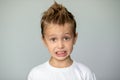 Cute boy shows a grimace. Detached young man on a gray background with even white teeth. Beautiful brown eyes wide open Royalty Free Stock Photo