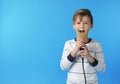 Cute boy singing in microphone on color background Royalty Free Stock Photo