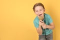 Cute boy singing in microphone on color background Royalty Free Stock Photo