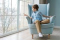 Cute boy sits in chair by window and looks out for something in window Royalty Free Stock Photo