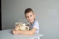 A cute boy sits near a transparent aquarium in the room and hugs an aquarium with fish Royalty Free Stock Photo