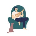 Cute boy sitting in comfy armchair and playing ukulele for his dog. Funny adorable musician with guitar and his domestic