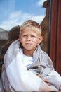 Cute boy sitting in a cozy blanket outdoors