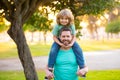 Cute boy sitting on fathers shoulders. Childhood and parenthood kids concept. Happy father and son playing together Royalty Free Stock Photo