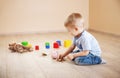 Cute boy sitting on the floor indoor and inserting euro coins in piggybank. Royalty Free Stock Photo