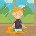 Cute boy sitting in lotus position and meditating, boy practicing yoga on the background of window with summer view Royalty Free Stock Photo