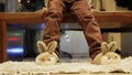 Cute boy sitting near the Christmas tree and playing with his new bunny slippers.