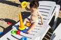 A cute boy is sitting on a sunbed on the beach and plays with toys . The concept of travel and adventure. Family trip