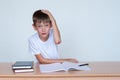 A cute boy is sitting at the table, a wound on the elbow. The child does not want to study, does not want to do homework Royalty Free Stock Photo