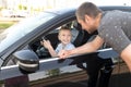 Cute boy is sitting at the wheel in the car, dad is looking out the car window Royalty Free Stock Photo