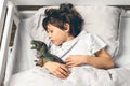 Cute boy is sleeping in bed with a toy dinosaur Royalty Free Stock Photo