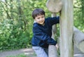 Cute boy with smiling face looking out, Candid shot happy kid playing in the park,Child having fun in a climbing on wooden fame Royalty Free Stock Photo