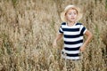 Cute boy in a straw hat and striped T-shirt looks away at a field of oats. He's playing hide and seek Royalty Free Stock Photo