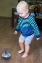 Cute boy in a striped sweater plays with whirligig on the floor Royalty Free Stock Photo