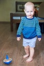 Cute boy in a striped sweater plays with whirligig on the floor Royalty Free Stock Photo