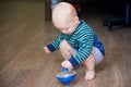 Cute boy in a striped sweater plays with whirligig on the floor Royalty Free Stock Photo