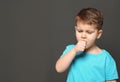 Cute boy suffering from cough on dark background