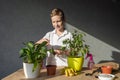 A cute boy takes care of indoor plants, loosen the ground with a soil tool, fertilize the soil Royalty Free Stock Photo