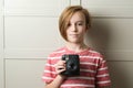 Cute boy taking selfe with photo camera. Stylish kid over grey background Royalty Free Stock Photo