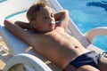 Cute boy taking sun near a swimming pool Royalty Free Stock Photo