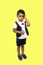 a cute boy talking on a cell phone. A little kid having a serious smartphone talking to him was isolated on the yellow background Royalty Free Stock Photo