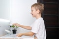 Cute boy turns on the water to wash his hands and wash , smiling Royalty Free Stock Photo