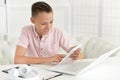 Cute boy using calculator while sitting at table Royalty Free Stock Photo