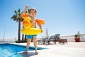 Cute boy waving hands standing on the edge of swimming pool