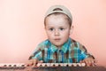 Cute boy wearing baseball cap backwards playing the digital piano Royalty Free Stock Photo