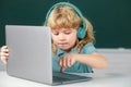 Cute boy wearing headphones, study with laptop in classroom, listening audio lesson course. Computer training. Royalty Free Stock Photo