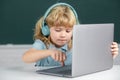 Cute boy wearing headphones, study with laptop in classroom, listening audio lesson course. Computer training. Royalty Free Stock Photo