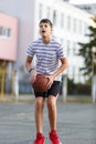 Cute boy in white t shirt plays  basketball on street  playground. Teenager  throws orange basketball ball outside. Royalty Free Stock Photo