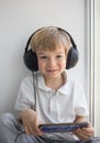 Cute boy 4-5 years old in big headphones and with a mobile phone, sits alone Royalty Free Stock Photo