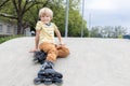 cute boy 7 years old on roller skates sits on the ground Royalty Free Stock Photo