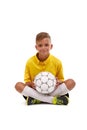 A cute boy in a yellow sport uniform holds a ball in his hands isolated on a white background. Royalty Free Stock Photo