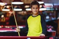 Cute boy in yellow t shirt plays billiard or pool in club. Young Kid learns to play snooker. Boy with billiard cue