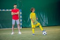 Cute boy in yellow uniform playing soccer, his coach watching him