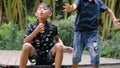 Cute boys are blowing a soap bubbles outside. Indonesian or malasian brother siblings are playing together outdoors