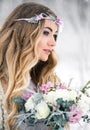 Cute bride in the winter snow forest outdoors with beautiful flowers on her head and a bouquet Royalty Free Stock Photo