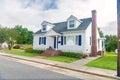 Cute brightly painted white shingled cottage with blue shutters. coastal town on cloudy day