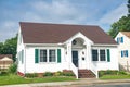 Cute brightly painted white shingled cottage with green shutters. coastal town on sunny day