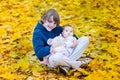 Cute brother holding his baby sister between yellow maple Royalty Free Stock Photo
