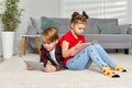 cute brother and sister with tablet lying on floor at home